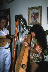 Jesus Rodriguez playing cuatro while apprentice Cecilia Santos plays Venezuelan harp- Miami, Florida.