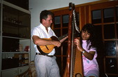 Jesus Rodriguez playing cuatro while apprentice Cecilia Santos plays Venezuelan harp- Miami, Florida.