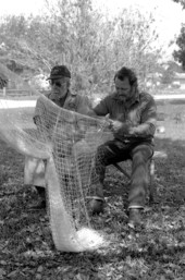 Apprentice Reginald Reis works on a cast net while master netmaker Max Dooley looks on - Lakeland, Florida.