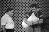 Greek bagpiper Nikitas Tsimouris of Tarpon Springs looks on as apprentice George Pilatos performs at the 1985 Florida Folk Festival - White Springs, Florida