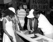 Basket maker Lucreaty Clark and other women look over a quilt at the Folk Festival- White Springs, Florida