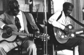 Rev. N.L. Williams playing blues guitar while "Blind" Johnny Brown plays a resonator guitar