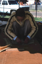 Tuyen Pham tying together pieces of whittled wood to make a rice basket - Pensacola, Florida.