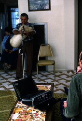 Nikitas Tsimouris playing the tsambouna while folklorist Blanton Owen watches and records- Tarpon Springs, Florida