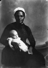 White-capped nurse holding an infant.