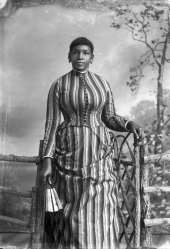 Woman in striped dress, holding a fan.