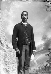 Man in striped tie and pants, holding newspaper.