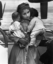 Young Cuban refugee holding her dolls in airport