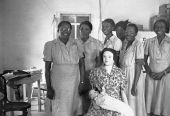 Midwives in training posing for photograph with delivery mannequin