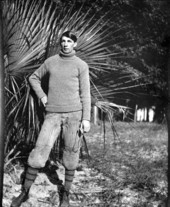 Uniformed football player holding face guard