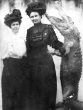 Two women posing with a stuffed alligator