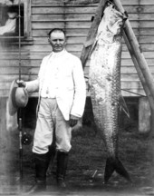 Dr. Cyrus R. Teed stands beside a tarpon.