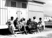 Migrant workers relaxing outside labor camp shelters - Belle Glade, Florida.