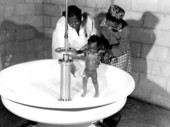 African American baby being given a bath at a migrant labor camp - Belle Glade, Florida.