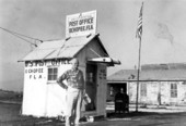 Postmaster Sidney H. Brown standing in front of the nation's smallest Post Office in Ochopee.