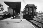 A young woman stands near "the Orange Blossom Special" train at railroad depot - Sebring, Florida.