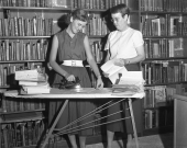 Dr. Dorothy Dodd and student flattening documents.