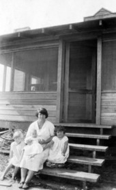 Woman sitting with her children on the steps of their new home - LaBelle, Florida.