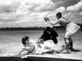 All American Girls Professional Baseball League player Marg Callaghan sliding into home plate as umpire Norris Ward watches - Opa-locka, Florida