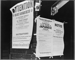 Posters taped to a brick wall, one with posted locations for air raid shelters in San Francisco and another directing the removal by April 7 of persons of Japanese ancestry.