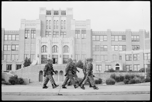 National Guard soldiers walking in formation in front of Central High School in Little Rock, Arkansas.