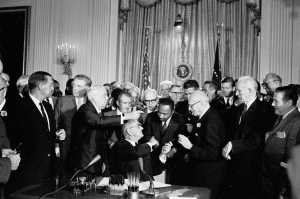 President Lyndon B. Johnson handing a pen to Dr. Martin Luther King, Jr. at the signing of the Civil Rights Act.
