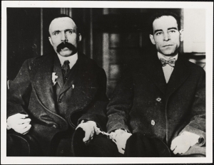 Nicola Sacco and Bartolomeo Vanzetti seated and handcuffed together.