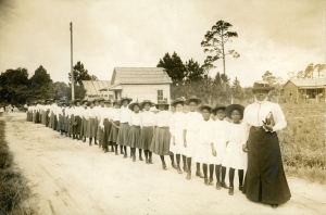 Mary McLeod Bethune standing on a long dirt road with a line of African American girls.