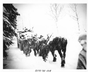 American infantrymen and a horse trudging behind an armored vehicle in the snow.