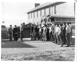 First 29 Navajo U.S. Marine Corps code-talkers being sworn in at Fort Wingate in New Mexico standing in front of a bus with their right hands raised.