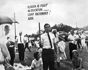 Florida teachers during their 1968 walkout with one male teacher holding up a sign that reads Florida is First in Education Count Backward Kirk.