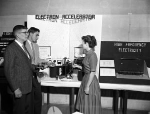 Three high school seniors gathered around a display with the title Electron Accelerator at the Big Bend Science Fair in Tallahassee, Florida.