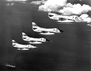 Four planes flying above an aircraft carrier during the Bay of Pigs Invasion.
